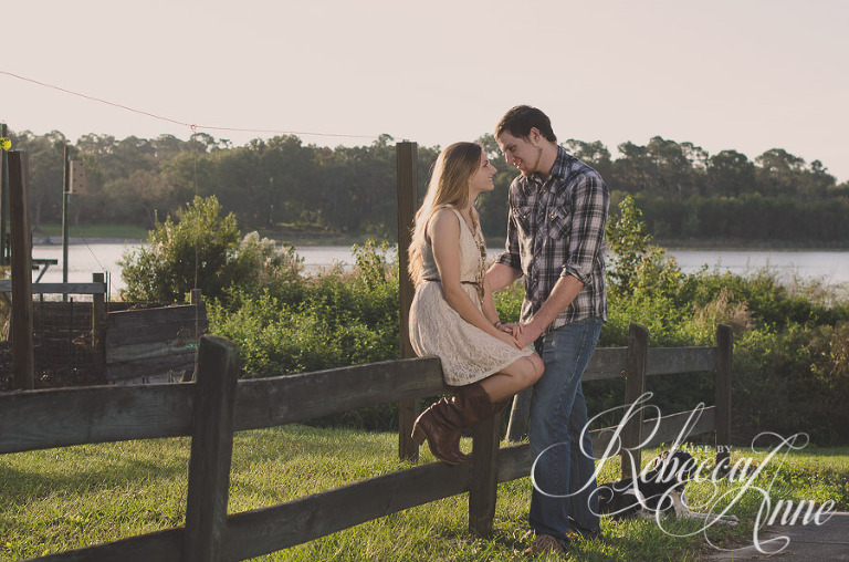 woman, girl, engagement couple, couple, lake, sunrise, embrace, hug, smile, flare, fence, dog