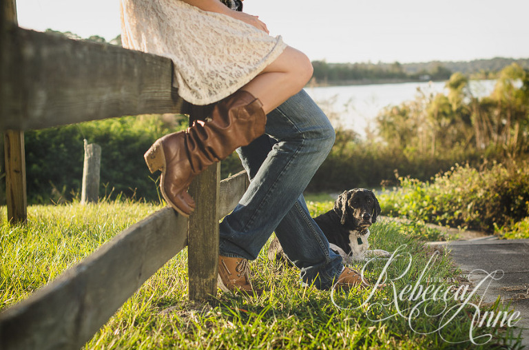 woman, girl, engagement couple, couple, lake, sunrise, embrace, hug, smile, flare, fence, dog, boots,